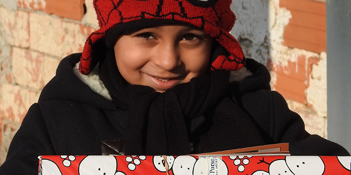 Boy in spiderman hat hold red shoebox in Macedonia