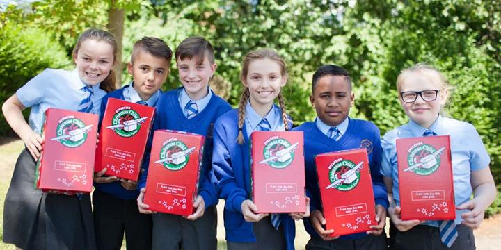 Group of school children holding shoeboxes