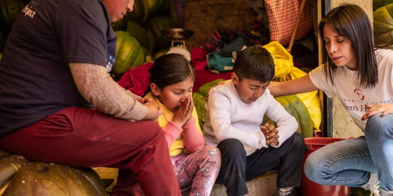 Daniela Acosta prays with Madelyn, her mother, and her brother. Patients hear the Good News of Jesus Christ throughout the surgery process. 