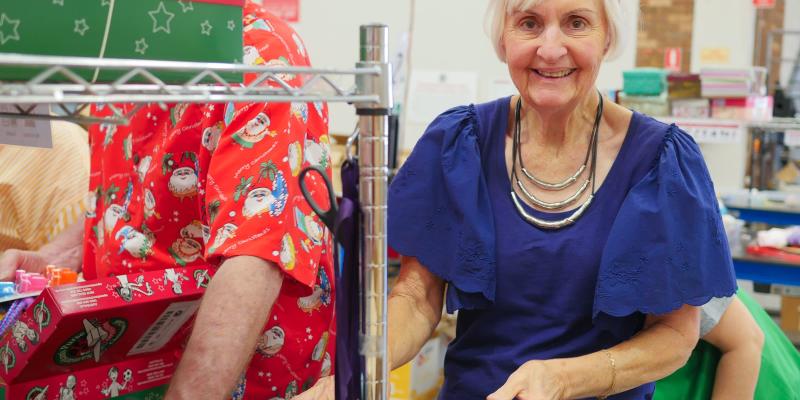 Volunteer wearing reindeer antlers smiles as she processes shoebox gifts