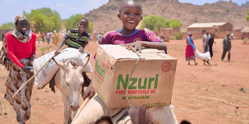 A little boy smiles as he brings home a food basket.