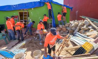 Volunteers from a Mexico City church place tarp on a damaged roof in the hillside neighborhoods of Acapulco.