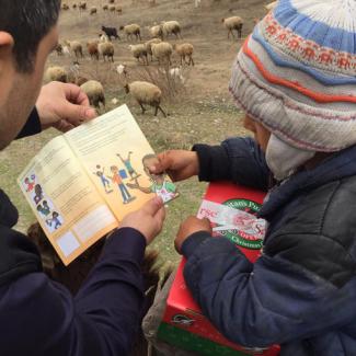 Yusif reads The Greatest Gift Gospel booklet to the younger brother.