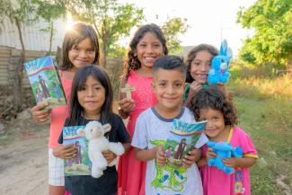 Children smiling with their The Greatest Journey manuals in hand