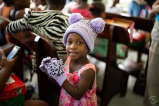 A GIRL SHOWS OFF THE NEW FASHION ACCESSORIES SHE DISCOVERED IN HER SHOEBOX. EVEN THOUGH IT WAS VERY HOT, SHE REFUSED TO TAKE THE GLOVES AND HAT OFF.