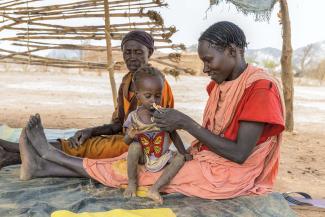 A MOTHER feeds her child a peanut paste supplement to help fight malnutrition.