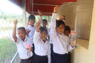 Primary school students give a thumbs up after filling their water bottles, because the clean water supplied by Samaritan’s Purse helps prevent disease that was once common there.