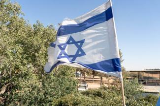 An Israeli flag flies as a symbol of hope over the southern kibbutz of Nir Oz that lost one in four of its residents to the October 2023 terrorist attacks.