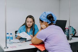 A Samaritan’s Purse clinic staffer shows a patient her new Bible after her health checkup.