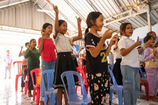 Phirun (in red) praises God during one of the classes for saving her from a life of thievery and bullying to walking with Him faithfully.