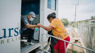 A Samaritan’s Purse medical staffer helps Amira onto the mobile medical unit for her consultation where she received medicine and a comprehensive health checkup.