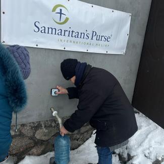 Kateryna fills her water bottle at the church tap.